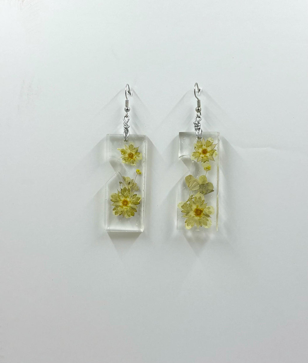 Rectangular clear earrings with pressed flowers on a light gray background