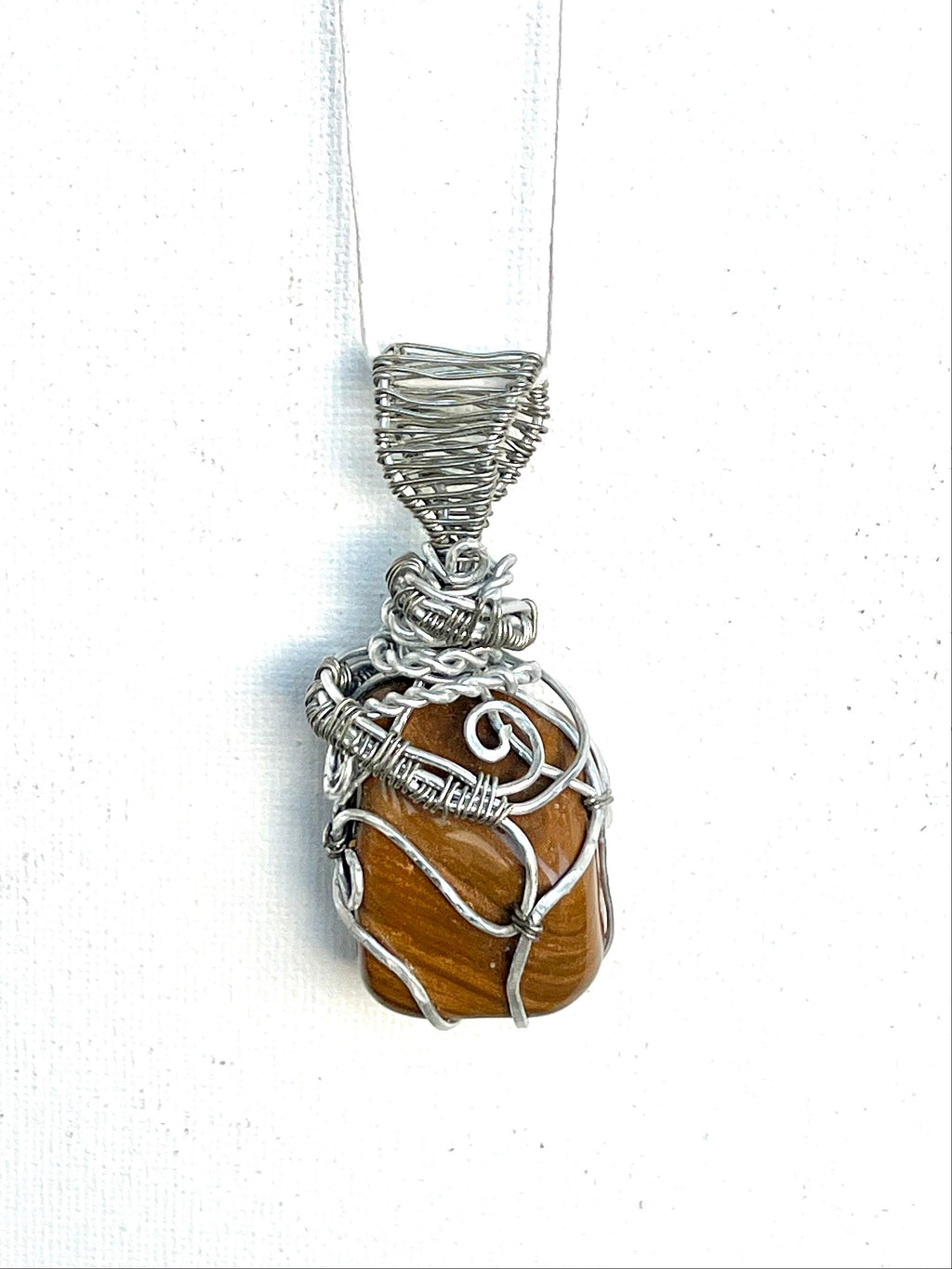 Pendant necklace with yellow jasper and silver wire wrapping on a white background