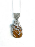 Pendant necklace with yellow jasper and silver wire wrapping on a white background