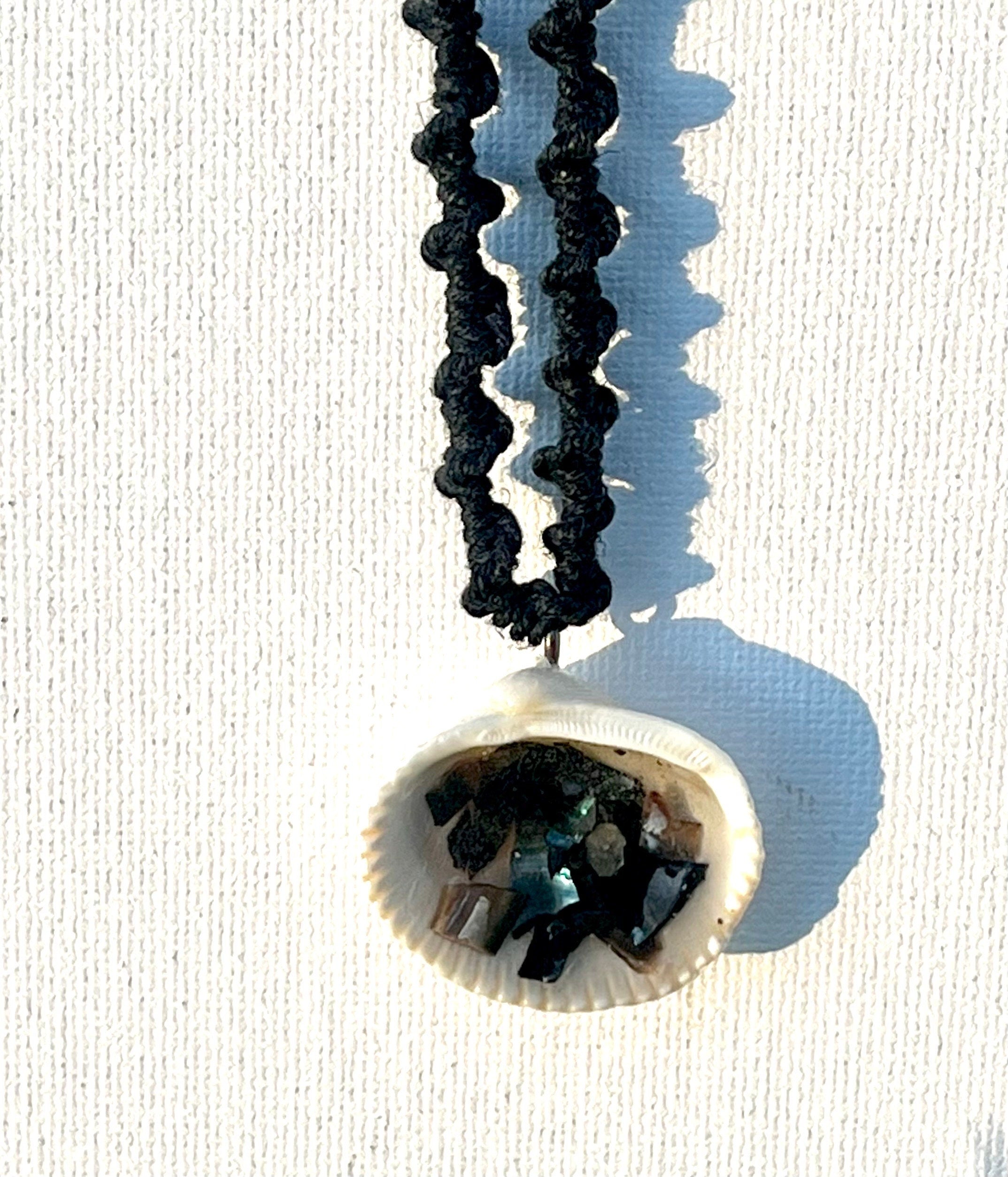 Necklace with a shell pendant featuring black and blue stones on a white background