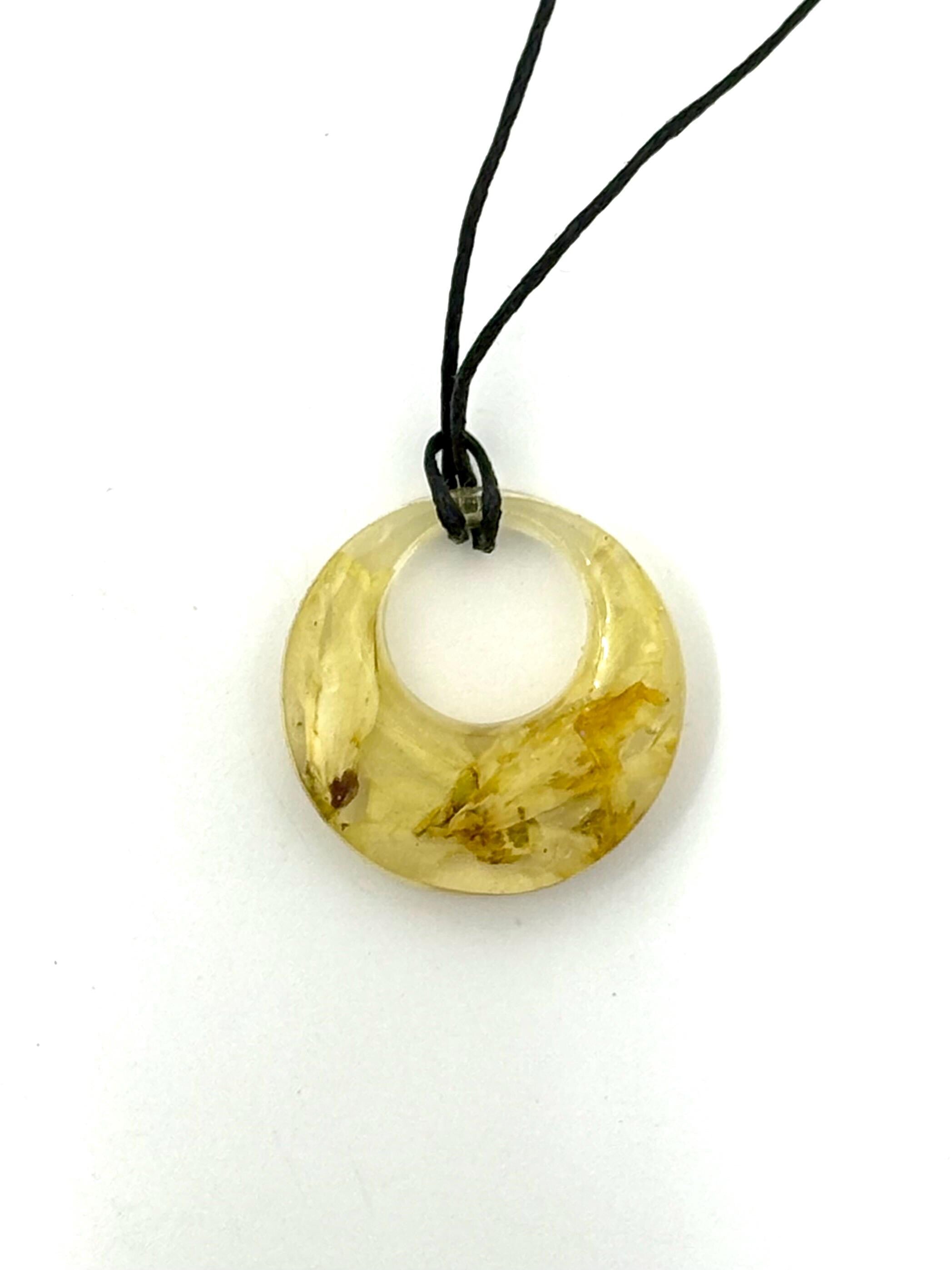 Round amber pendant on a black cord against a white background