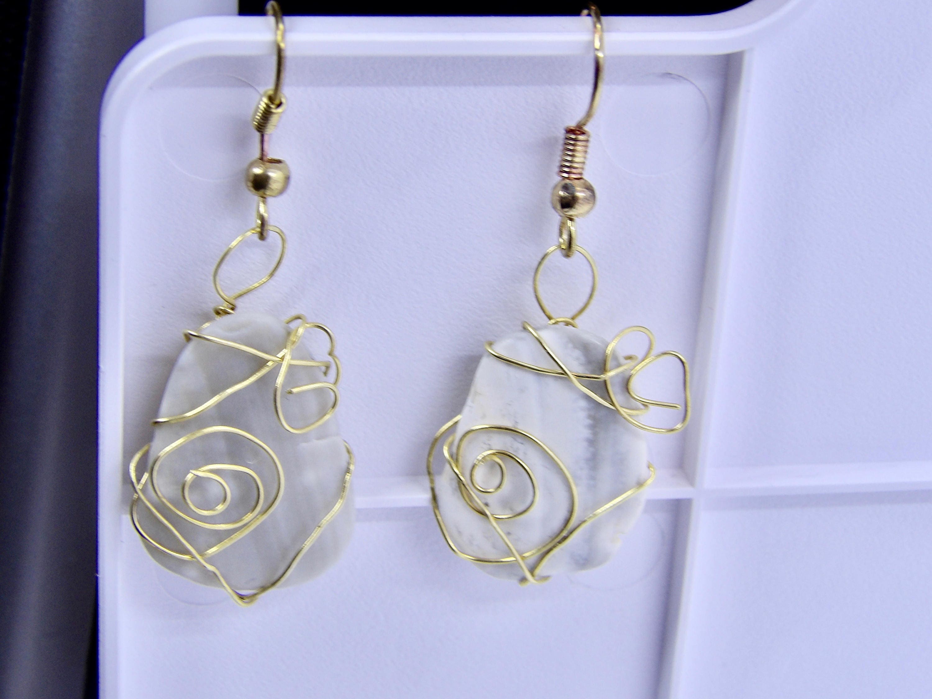 Pair of earrings with gold wirework on a white background