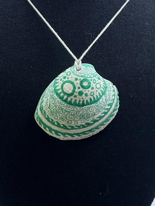 Decorative shell pendant with green patterns on a black background