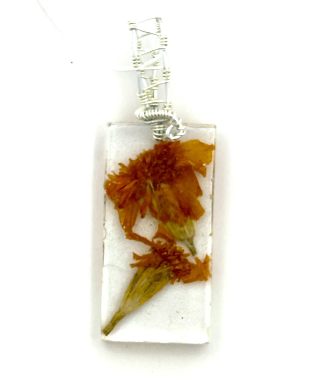 Rectangular pendant with dried flowers inside a clear case, on a white background
