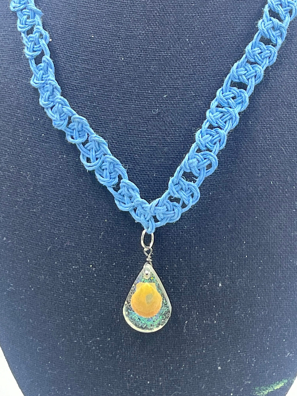 Blue knitted necklace with a teardrop pendant on a dark background