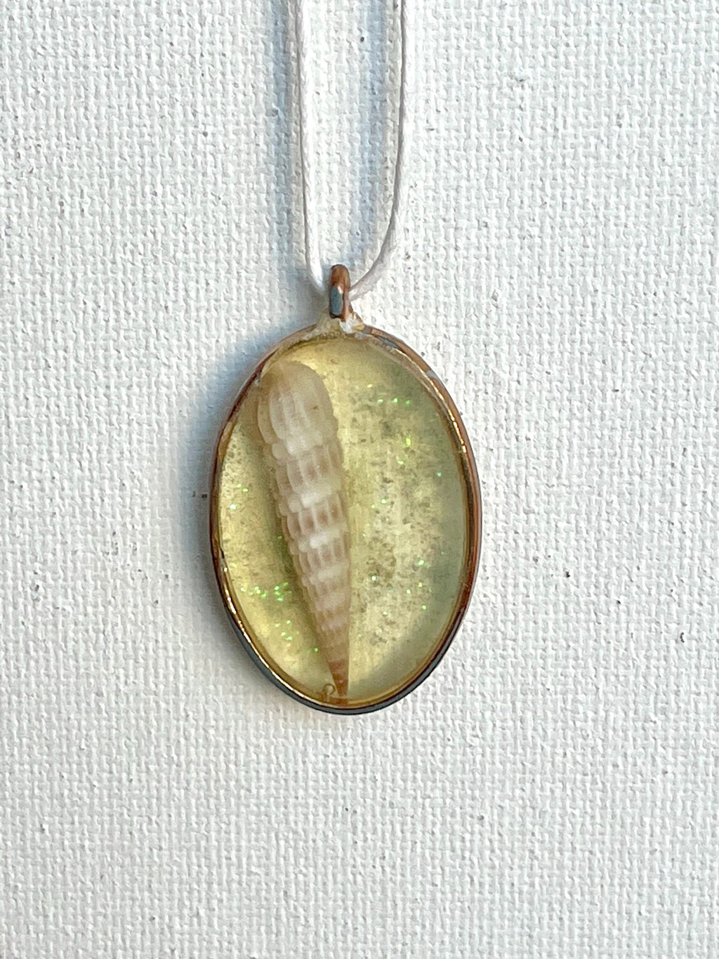 Pendant with shell inside a clear resin casing on a white background