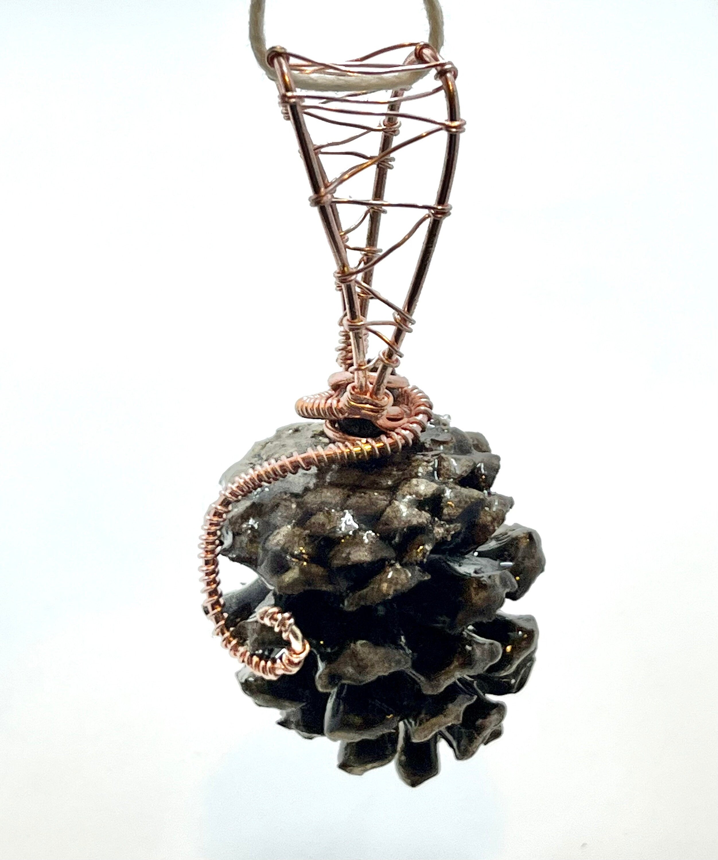 Pine cone pendant with copper wire wrapping on a white background