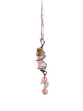 Decorative hanging pendant with pink beads and a small bottle on a white background