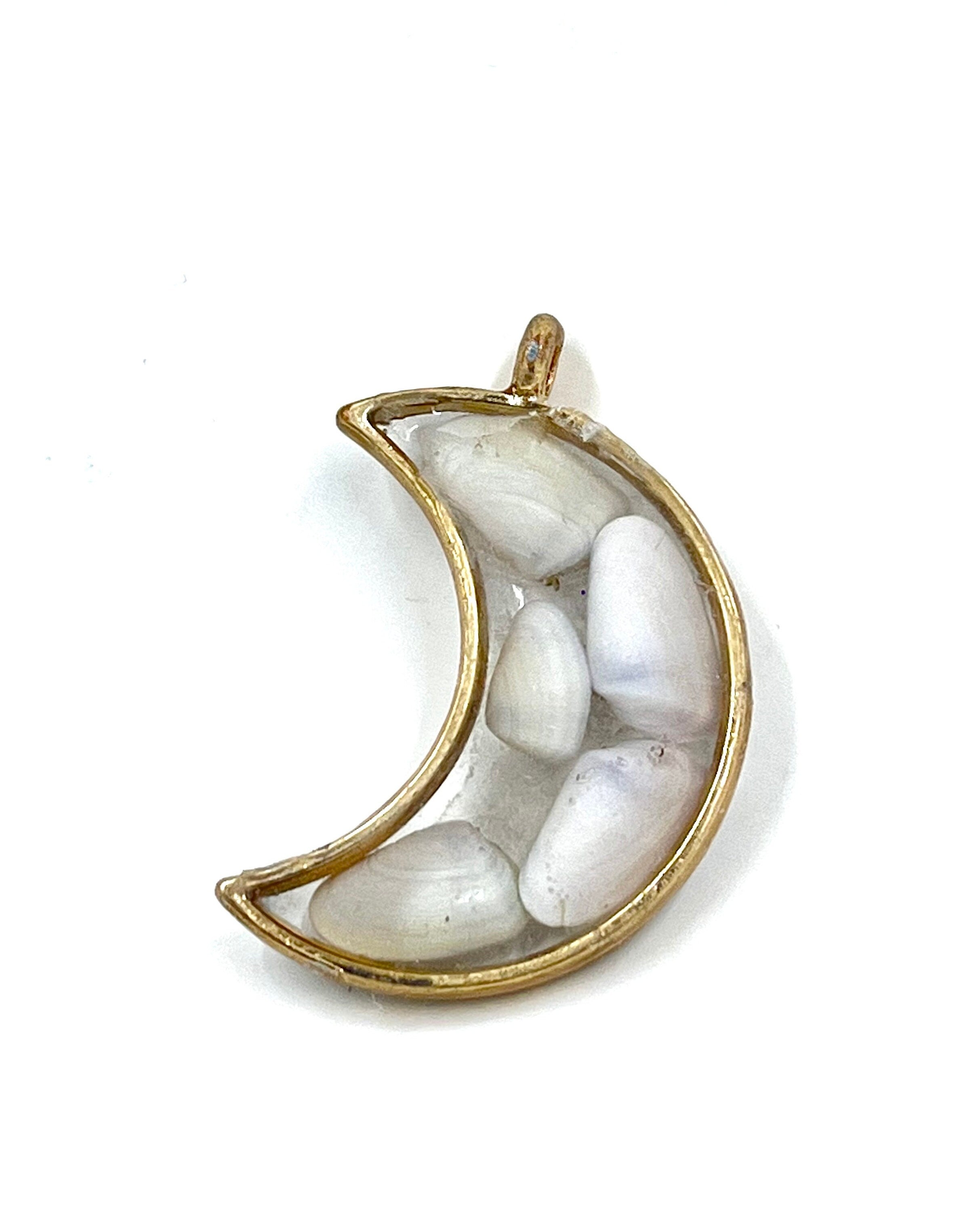Gold crescent moon-shaped pendant with white shells on a white background