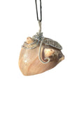 Shell pendant with decorative wirework on a white background
