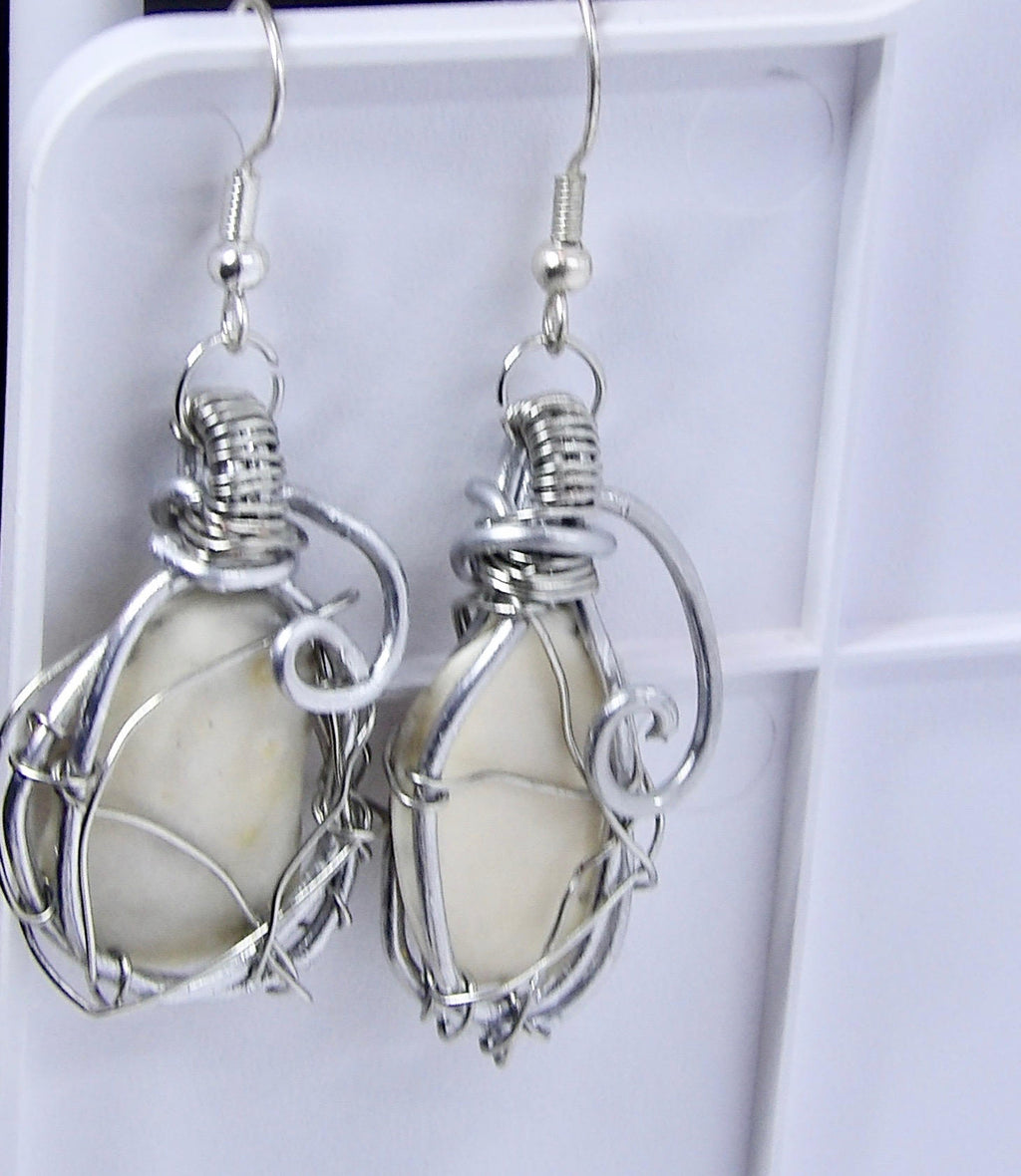 Silver wire-wrapped earrings with white shells on a white background