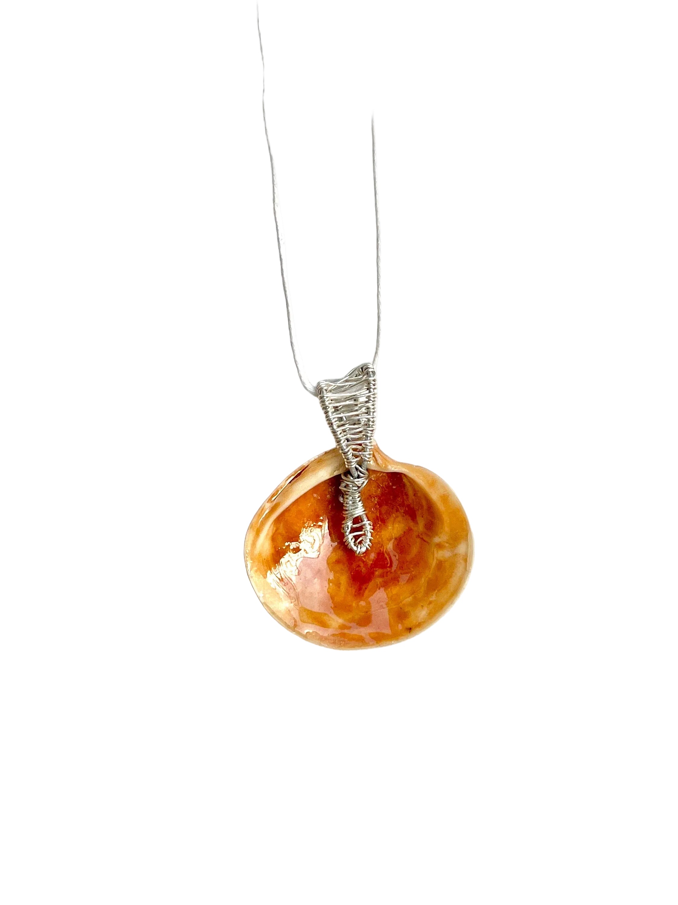 Necklace with a round orange shell pendant on a white background