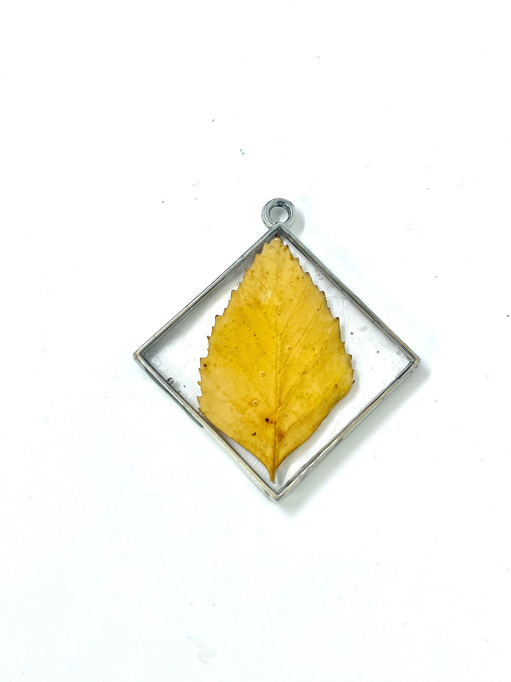 Yellow leaf pendant in a silver frame on a white background