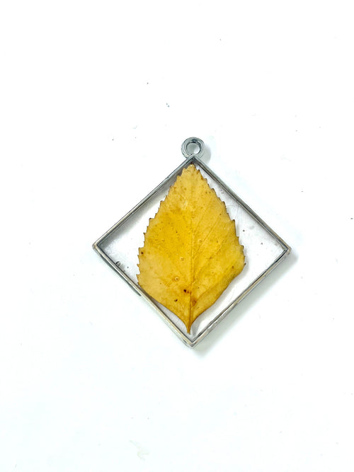 Yellow leaf pendant in a silver frame on a white background